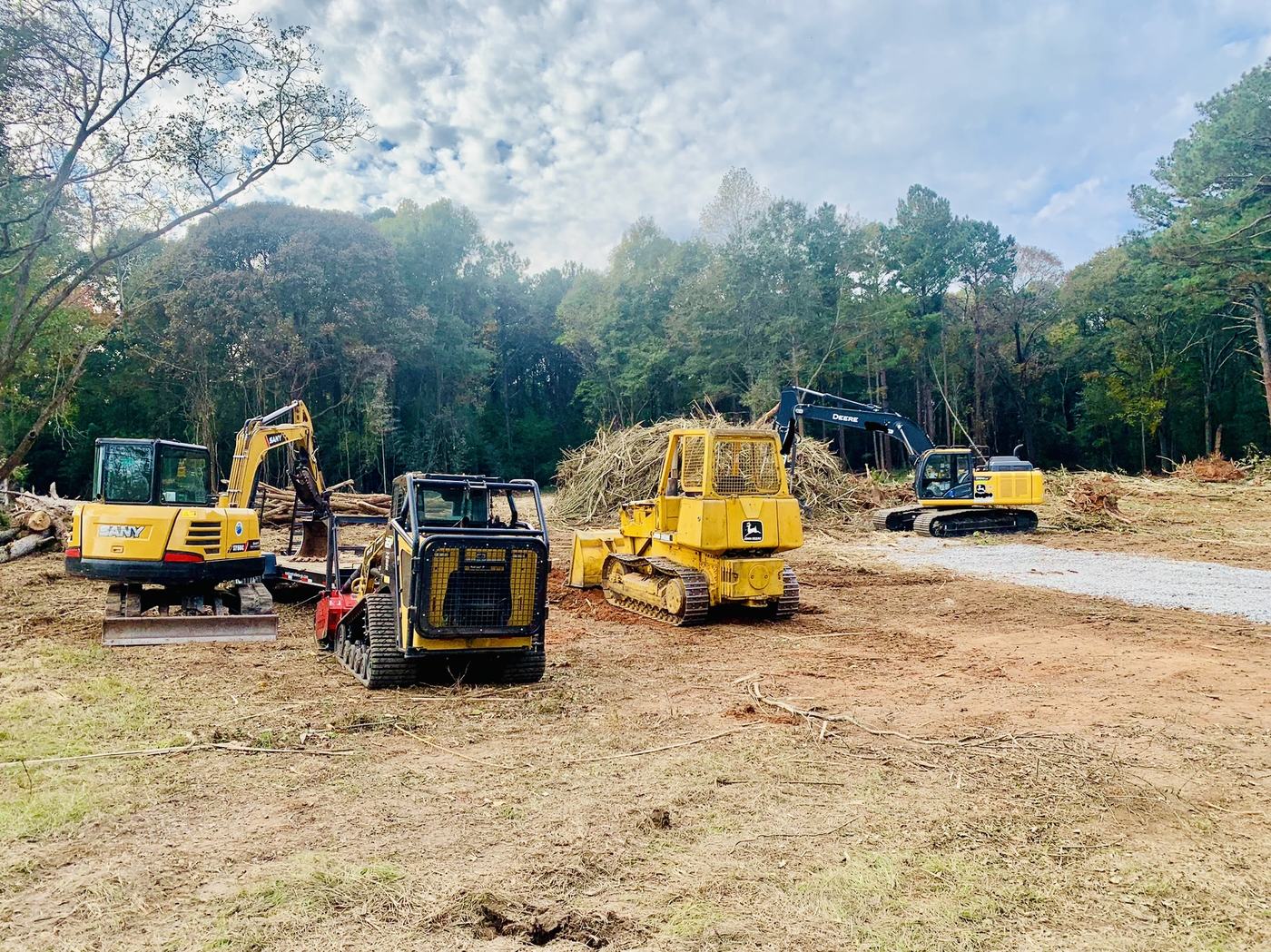 Excavators, a mulcher, and a crawler loader clearing a bamboo-choked lot