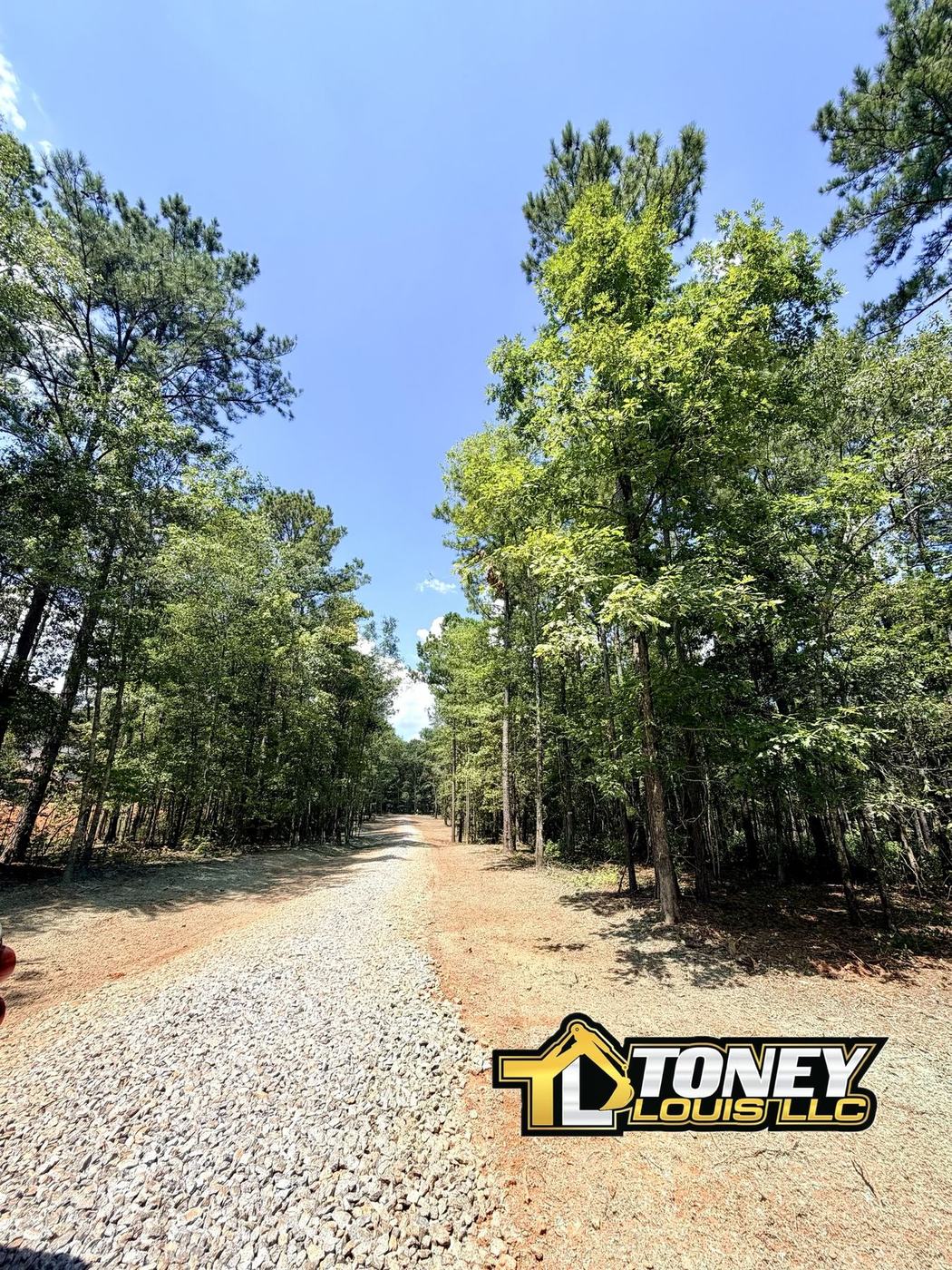New gravel driveway cut through a wooded residential parcel