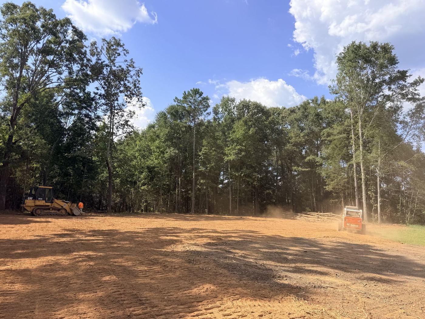 CAT track loader and Bobcat clearing a wooded lot down to bare ground